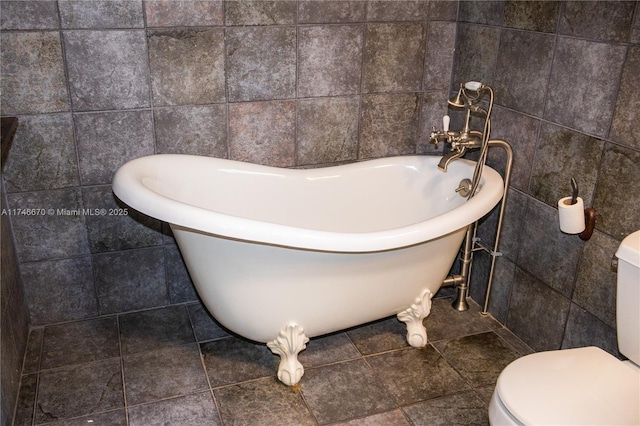 bathroom with toilet, tile walls, a soaking tub, and tile patterned flooring