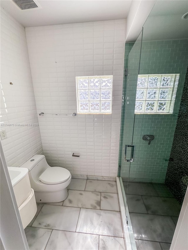 full bath featuring visible vents, toilet, marble finish floor, tile walls, and a shower stall