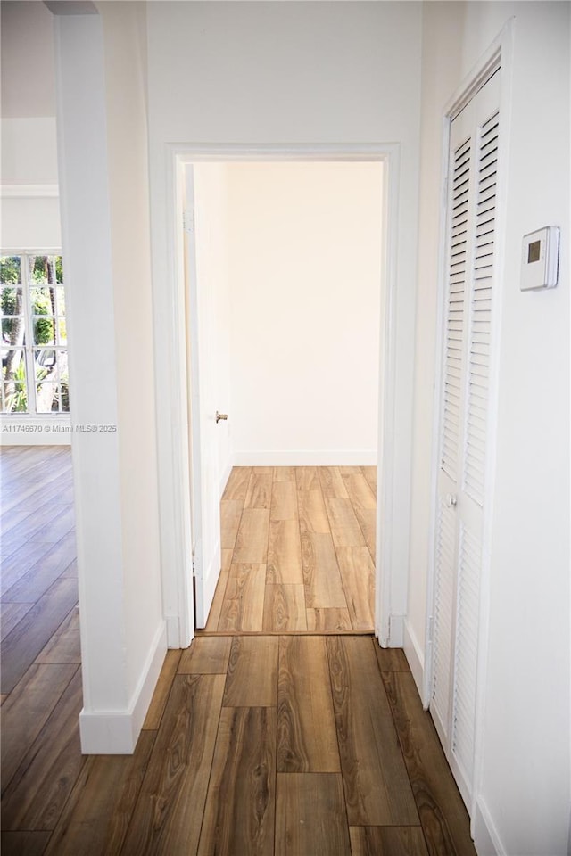 hallway featuring baseboards and wood finished floors