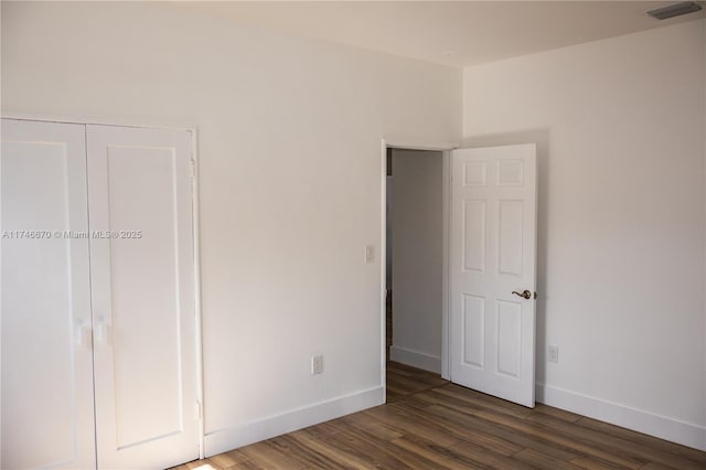 unfurnished bedroom with a closet, visible vents, baseboards, and wood finished floors