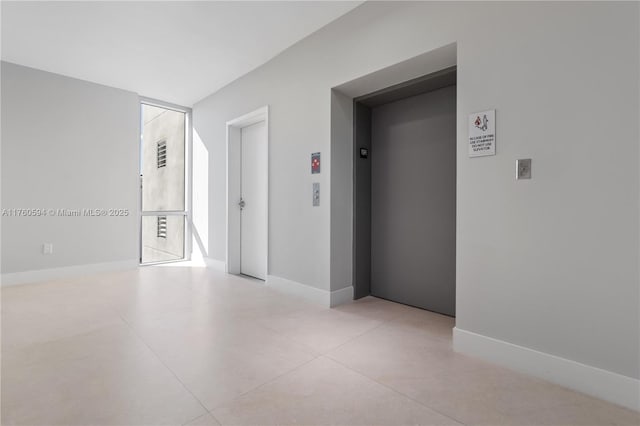 unfurnished room featuring baseboards, elevator, and concrete flooring