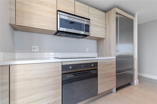 kitchen with light tile patterned floors, light brown cabinets, black appliances, light countertops, and modern cabinets