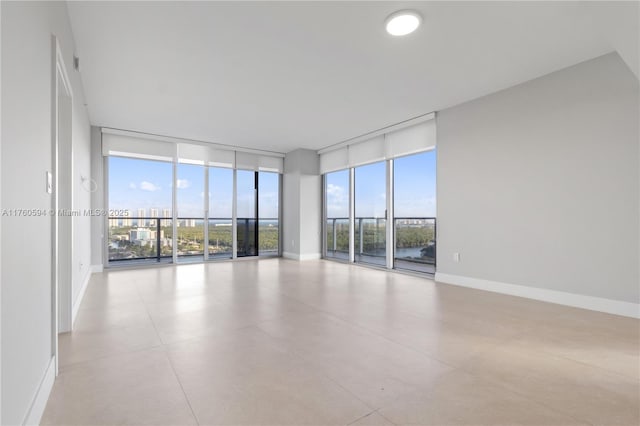 unfurnished room with a wall of windows and baseboards