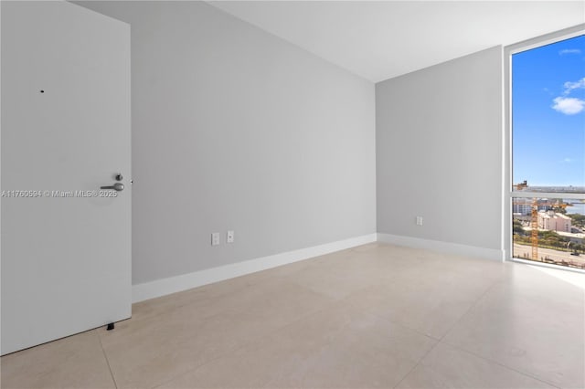 empty room with expansive windows, baseboards, and concrete floors