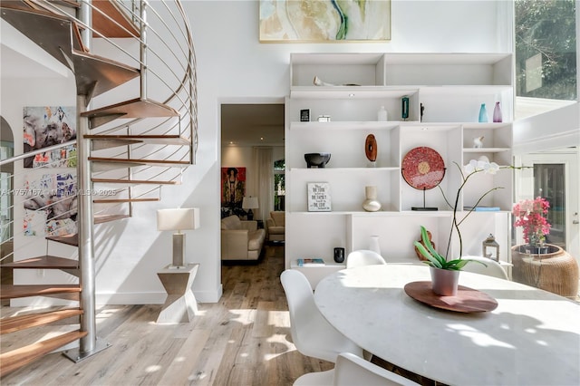 interior space with baseboards, wood finished floors, a towering ceiling, and stairs