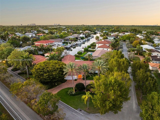 aerial view at dusk featuring a residential view and a water view