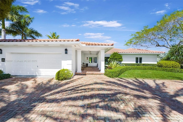 1117 Bella Vista Ave, Coral Gables, FL 33156 - mediterranean / spanish-style house with stucco siding, an attached garage, a tile roof, french doors, and decorative driveway
