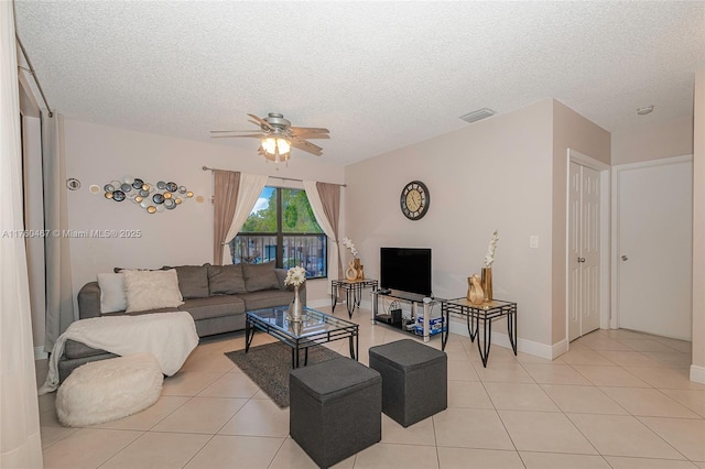 living area featuring visible vents, a textured ceiling, light tile patterned floors, baseboards, and ceiling fan