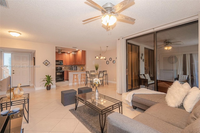 living area featuring visible vents, baseboards, light tile patterned floors, ceiling fan with notable chandelier, and a textured ceiling