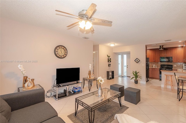 living area featuring ceiling fan, baseboards, a textured ceiling, and light tile patterned flooring