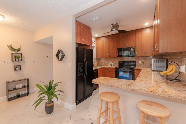 kitchen featuring light tile patterned floors, visible vents, a peninsula, black appliances, and tasteful backsplash