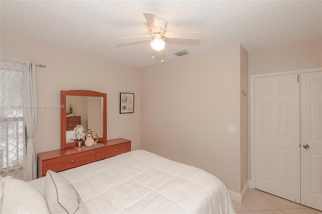 bedroom with light tile patterned floors, visible vents, a textured ceiling, and ceiling fan