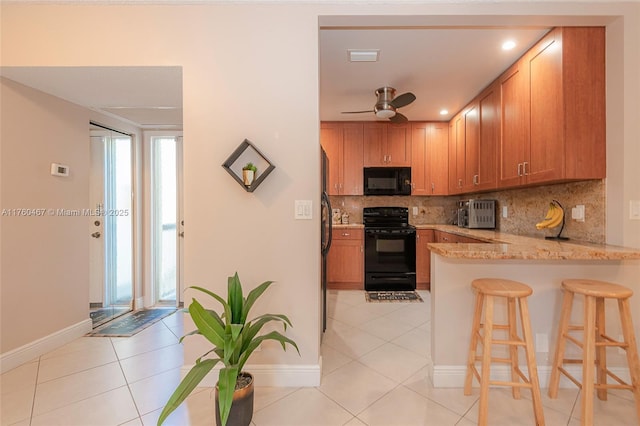 2888 S Carambola Cir S Unit 2079, Coconut Creek, FL 33066 - kitchen with black appliances, light tile patterned flooring, a peninsula, decorative backsplash, and a kitchen bar