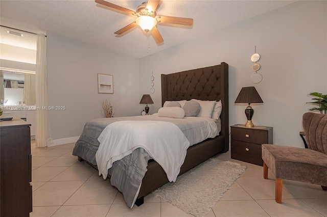 bedroom with baseboards, a textured ceiling, light tile patterned flooring, and a ceiling fan