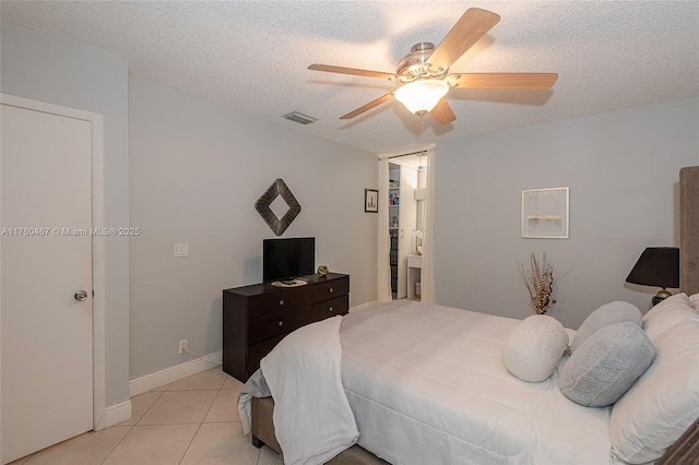 bedroom featuring baseboards, visible vents, light tile patterned flooring, ceiling fan, and a textured ceiling