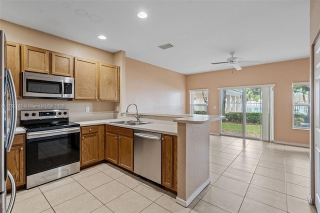 kitchen featuring visible vents, a sink, appliances with stainless steel finishes, a peninsula, and light tile patterned floors