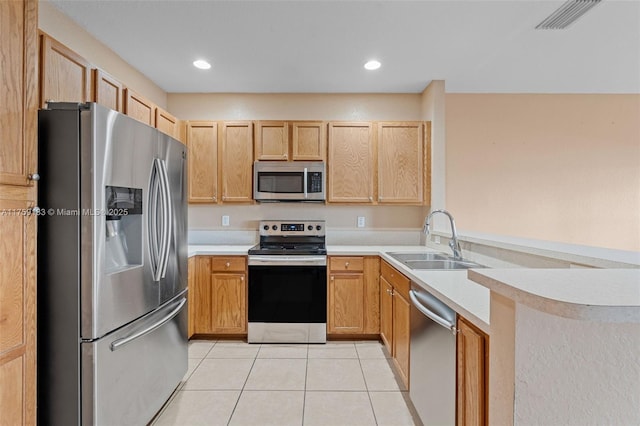 kitchen featuring a sink, appliances with stainless steel finishes, a peninsula, light tile patterned flooring, and light countertops