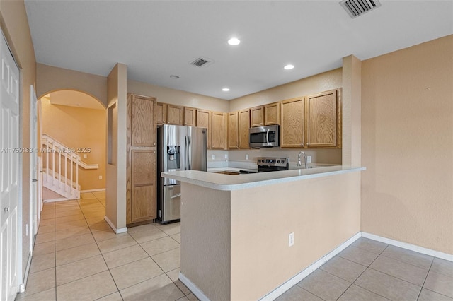 kitchen featuring stainless steel appliances, arched walkways, visible vents, and light countertops