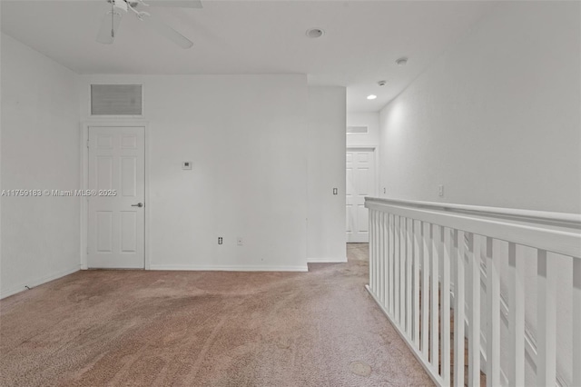 carpeted spare room with baseboards, visible vents, and ceiling fan