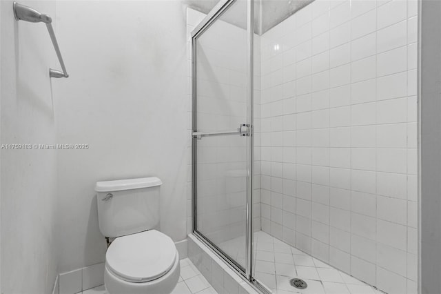 bathroom with a shower stall, toilet, and baseboards