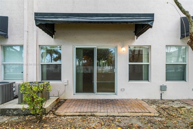 property entrance featuring a patio, central AC, and stucco siding