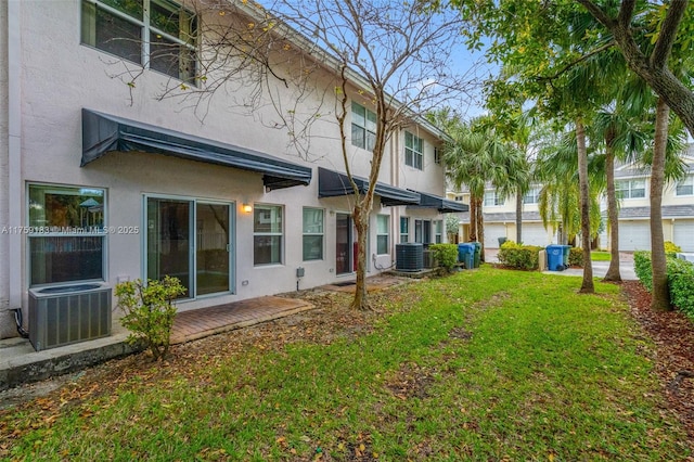 back of house featuring stucco siding, central air condition unit, and a yard