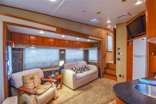 carpeted living area featuring recessed lighting, visible vents, and a sink