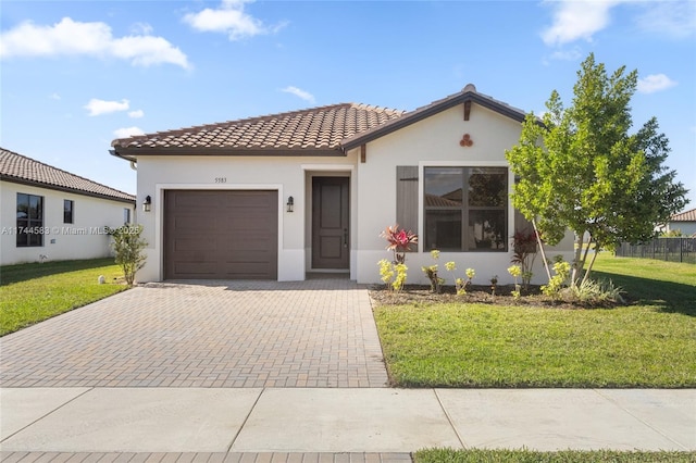 mediterranean / spanish-style house with stucco siding, a tile roof, decorative driveway, an attached garage, and a front yard