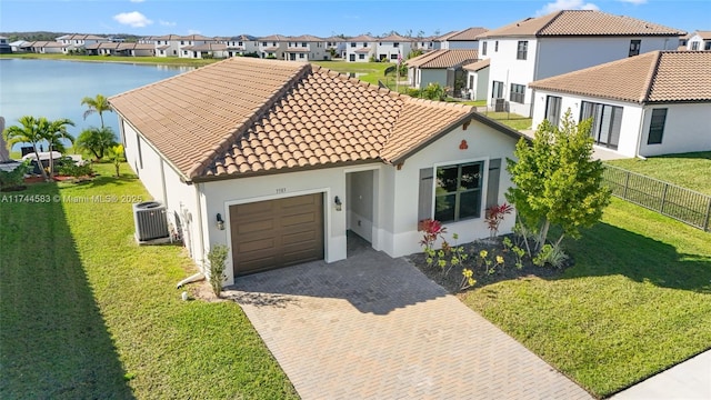 mediterranean / spanish house featuring central air condition unit, a residential view, a tiled roof, decorative driveway, and a garage