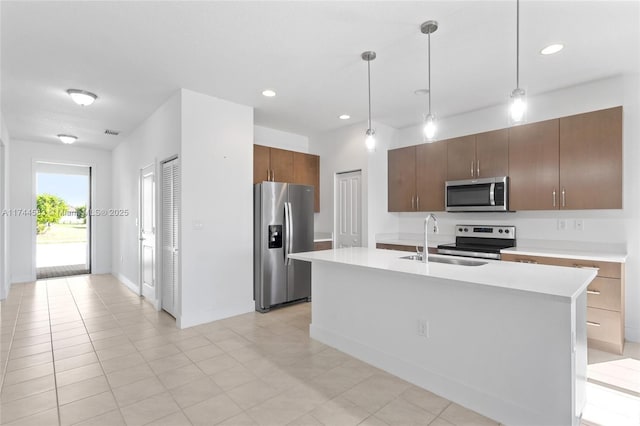 kitchen with light countertops, decorative light fixtures, appliances with stainless steel finishes, and a sink