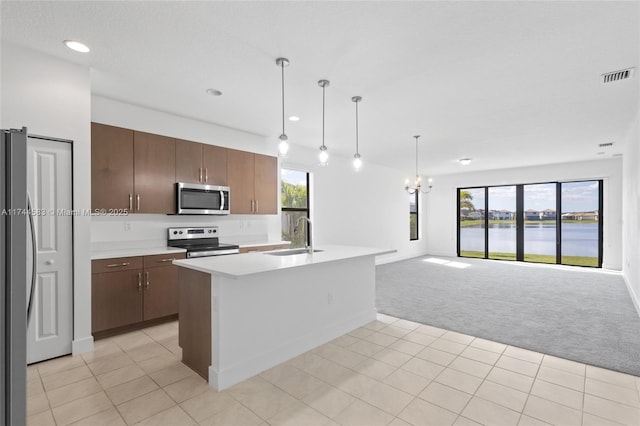 kitchen featuring visible vents, a sink, open floor plan, appliances with stainless steel finishes, and light colored carpet