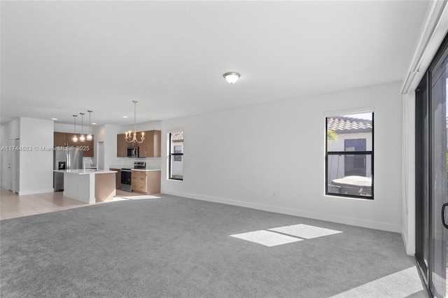 unfurnished living room featuring light carpet, a sink, light tile patterned floors, baseboards, and a chandelier