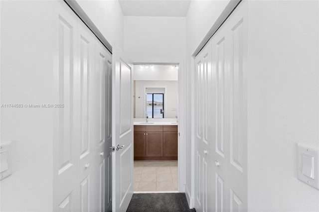 corridor featuring a sink, light colored carpet, and light tile patterned floors