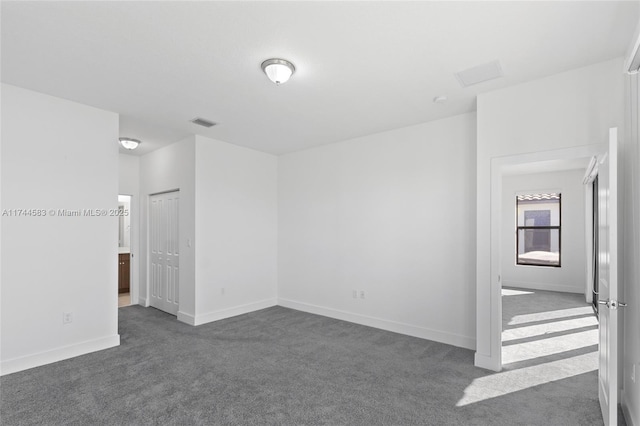 unfurnished room featuring baseboards, visible vents, and dark carpet