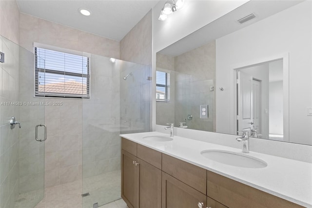 bathroom featuring a sink, visible vents, double vanity, and a shower stall