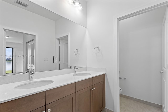 bathroom with a sink, visible vents, toilet, and double vanity