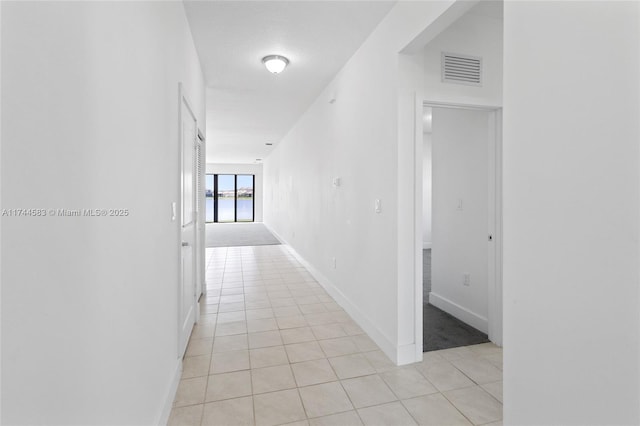 hallway with visible vents, baseboards, and light tile patterned flooring