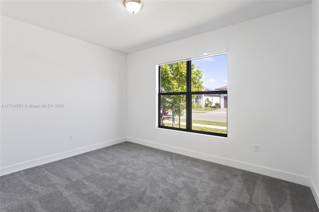 empty room with baseboards and dark carpet