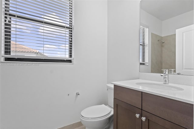 bathroom with a shower, toilet, a healthy amount of sunlight, and vanity