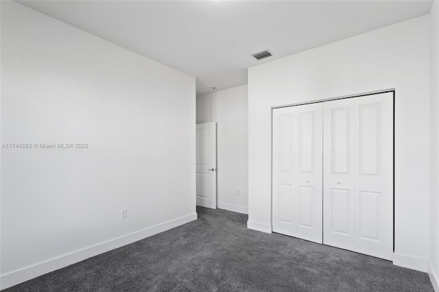 unfurnished bedroom featuring visible vents, baseboards, a closet, and dark carpet