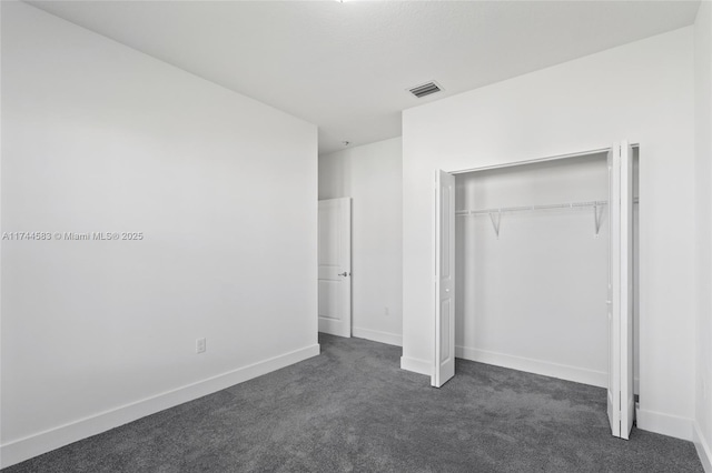 unfurnished bedroom with a closet, visible vents, dark carpet, and baseboards