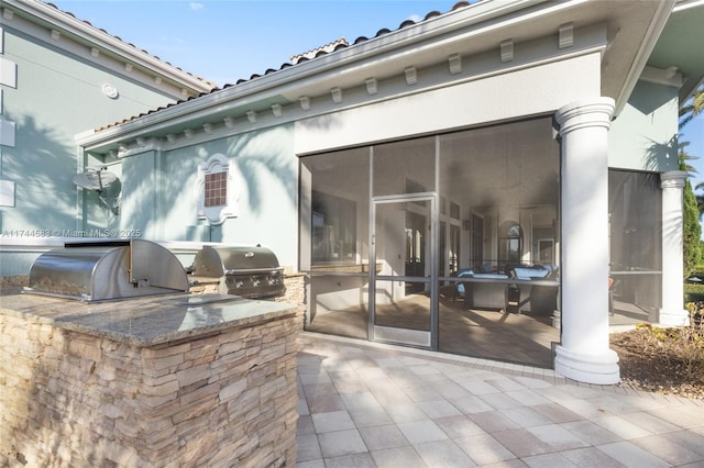 view of patio / terrace with exterior kitchen, area for grilling, and a sunroom