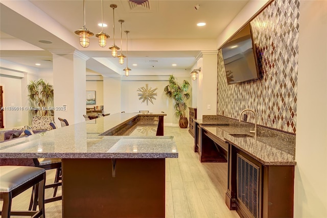 kitchen with dark stone countertops, visible vents, light wood finished floors, a sink, and open floor plan