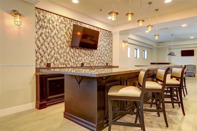 bar with baseboards, visible vents, wet bar, pendant lighting, and an accent wall