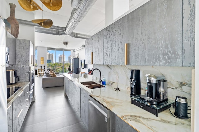 kitchen with modern cabinets, light stone countertops, appliances with stainless steel finishes, and a sink