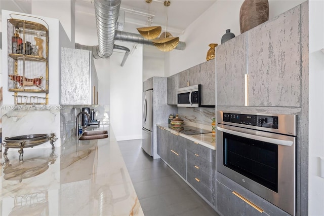 kitchen featuring a sink, a towering ceiling, appliances with stainless steel finishes, modern cabinets, and tasteful backsplash