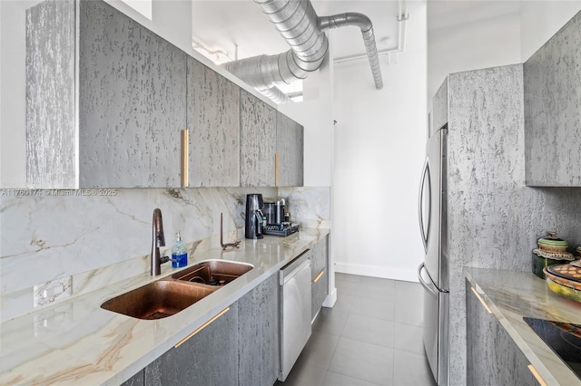 kitchen with a sink, tasteful backsplash, freestanding refrigerator, dishwashing machine, and light stone countertops