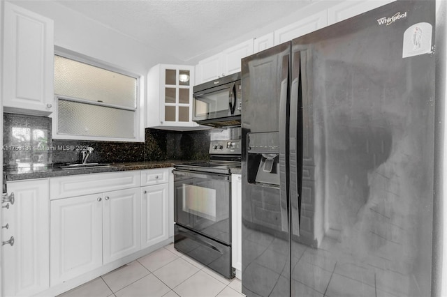 kitchen with black appliances, decorative backsplash, light tile patterned flooring, white cabinetry, and a sink