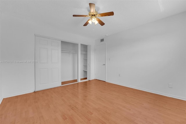 unfurnished bedroom with a ceiling fan, baseboards, visible vents, light wood finished floors, and a closet