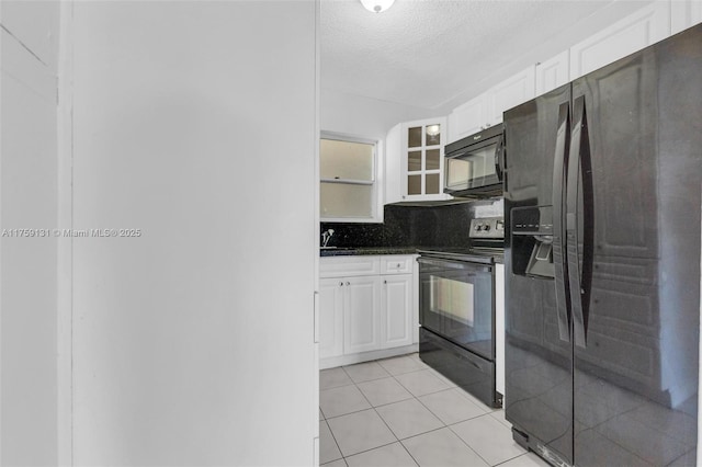 kitchen featuring dark countertops, white cabinets, black appliances, and a sink